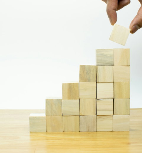 A person placing a piece of wood into a pyramid